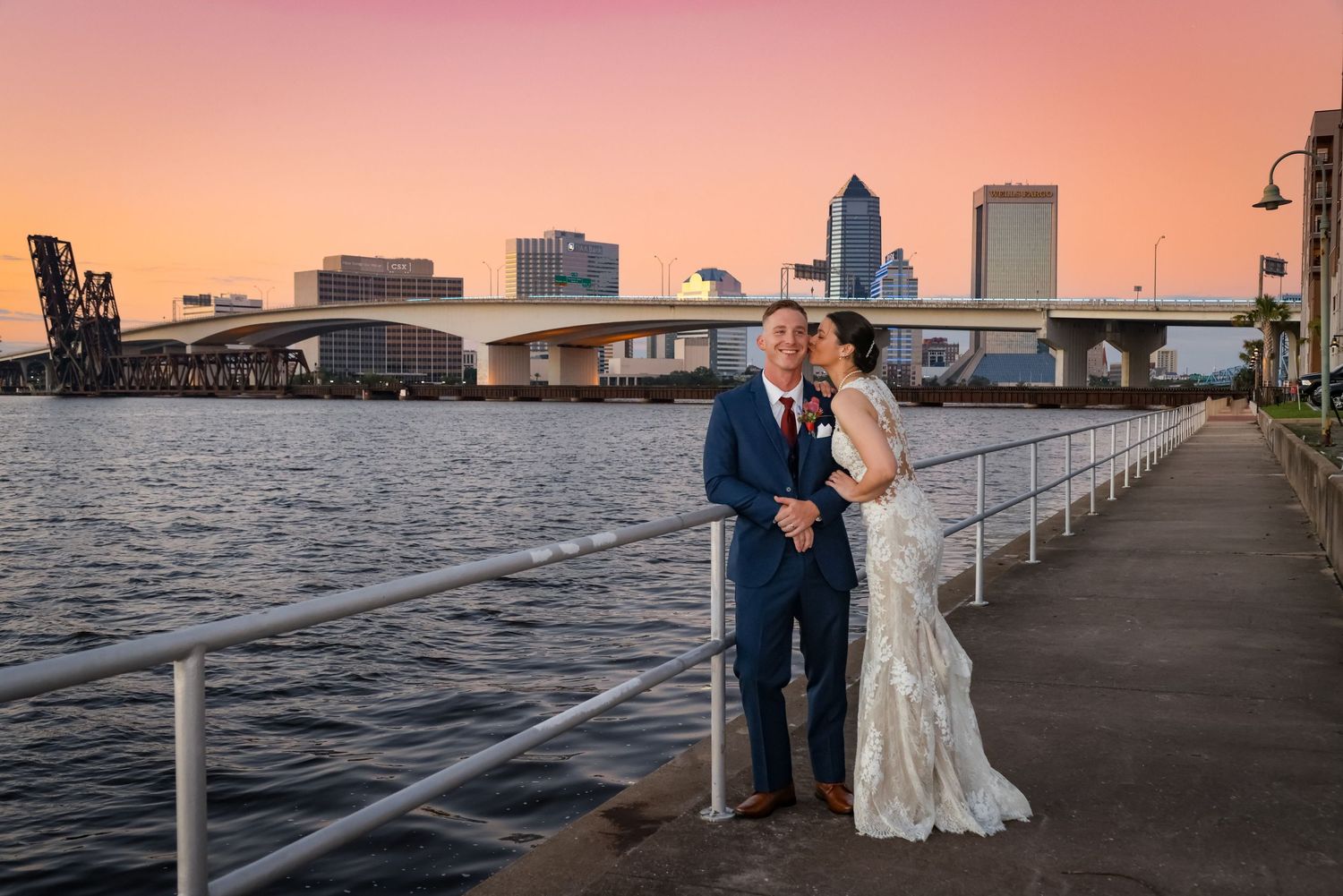 A sunset waterfront wedding portrait with Jacksonville's skyline and bridge in the background.