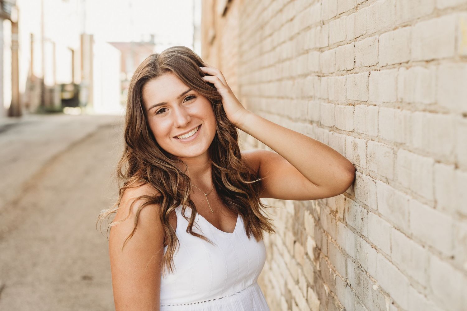 Bright outdoor portraits against white brick wall with natural lighting.