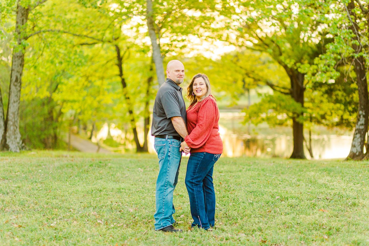 Couple in casual wear sharing a romantic moment on a grassy hill during golden hour.