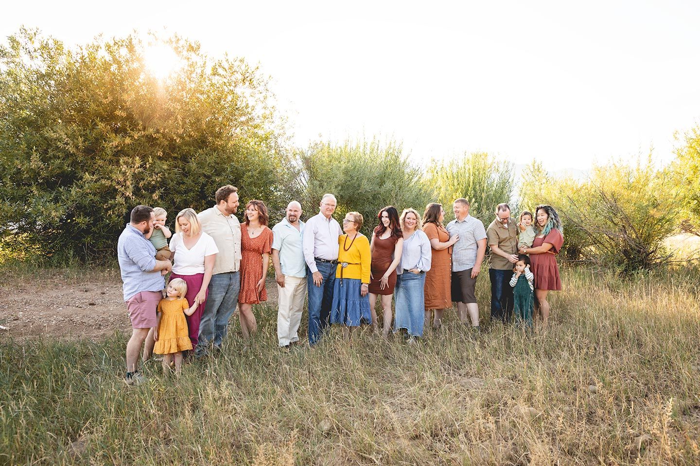 large extended family standing together outdoors, left to right with all the kids, aunts, uncles, and grandparents