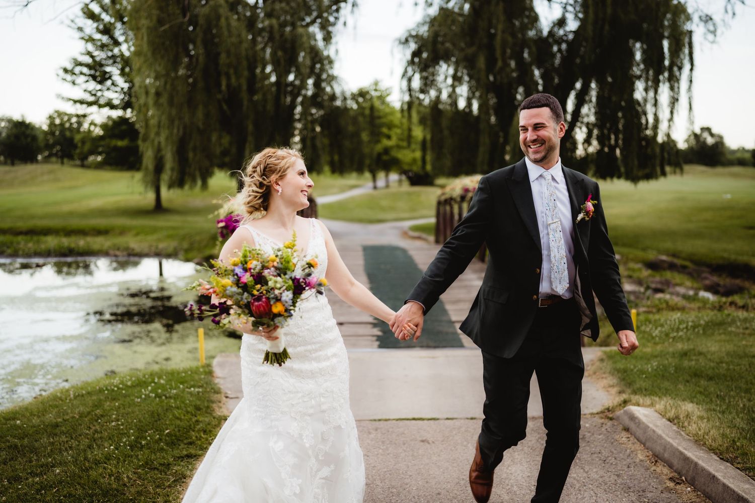A happy couple walking hand in hand through a scenic garden setting on their wedding day.