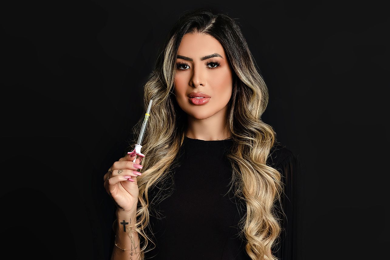Studio portrait against black background featuring long blonde waves and a black top.
