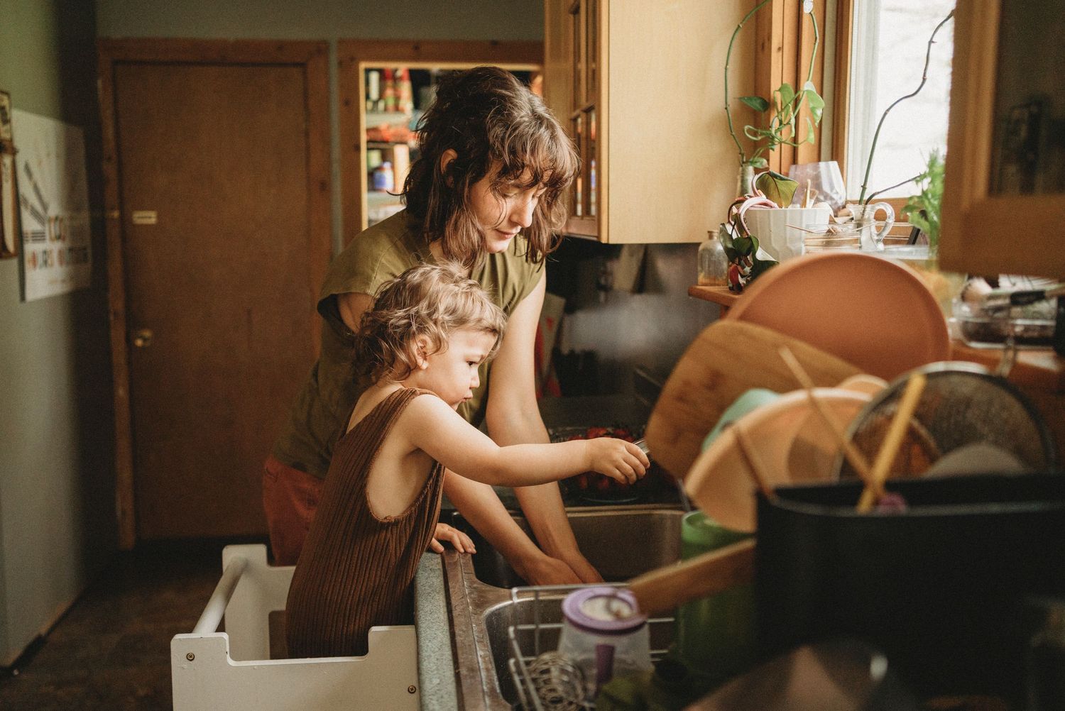 A warm kitchen scene of washing dishes together at the sink.