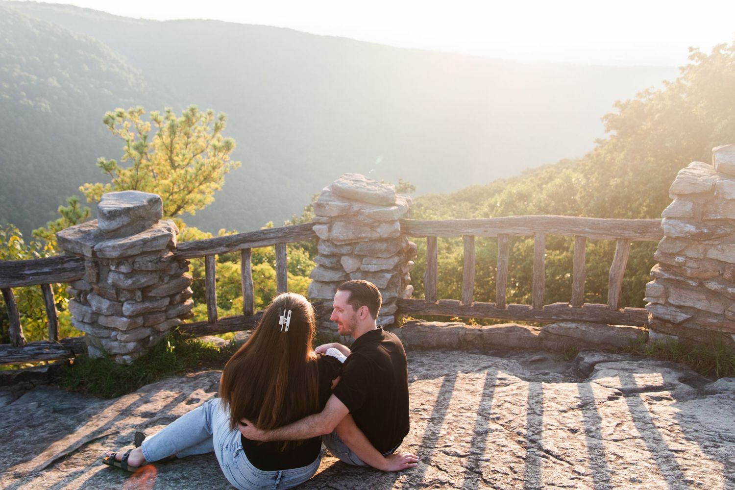 Couple sitting on stone overlook during sunset in the mountains.