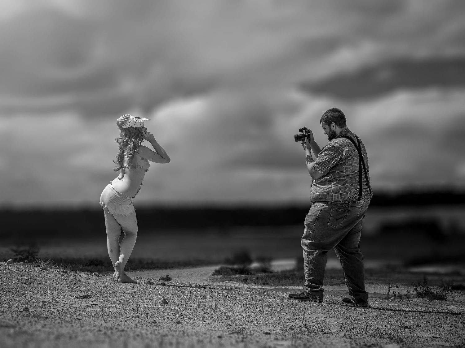 Black and white photo of photographer shooting model on coastal landscape.