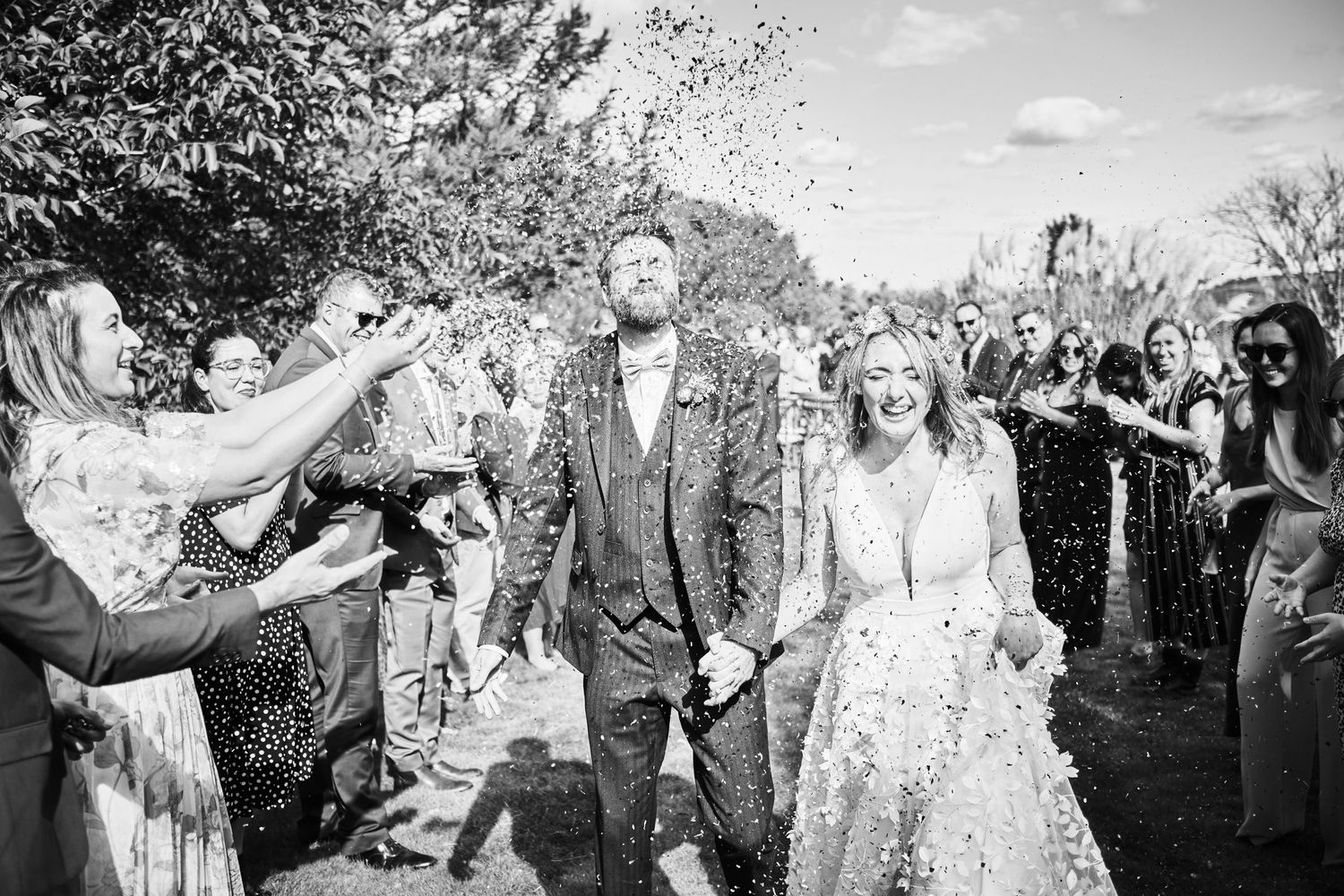Black and white photo of wedding celebration with confetti toss outdoors.