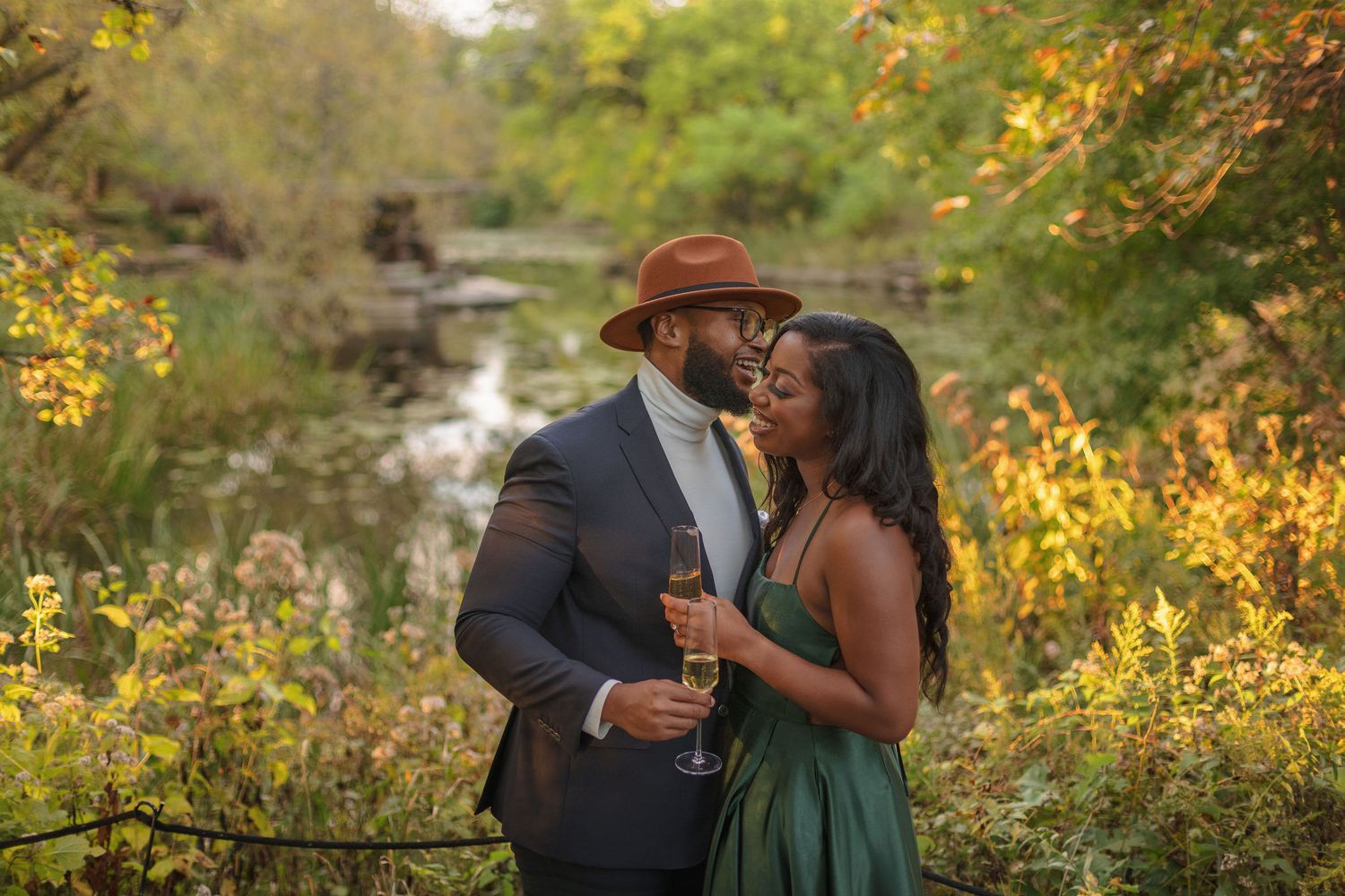 A romantic couple shares an intimate moment in front of a scenic autumn creek.