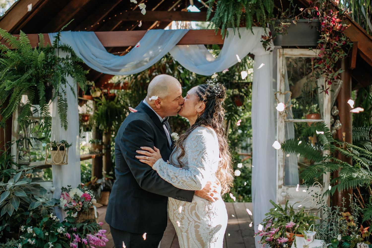 Couple sharing intimate moment under floral decorated wedding arch.