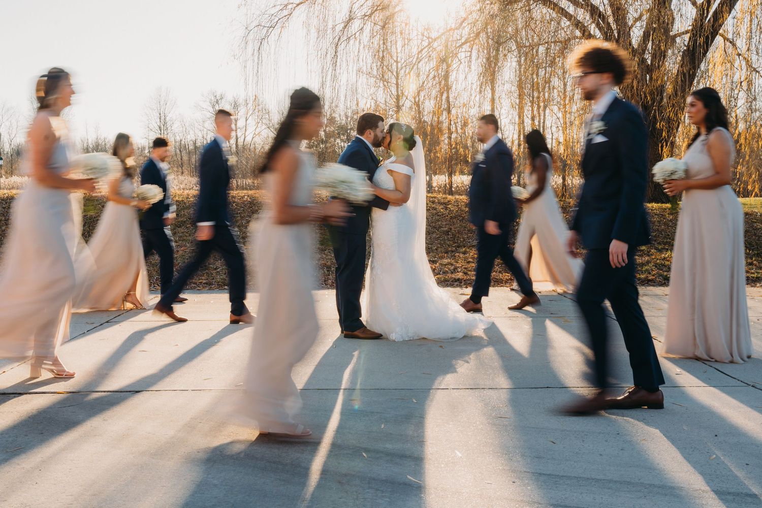 Wedding party silhouettes dancing in a line during sunset creating dramatic shadows on outdoor dance floor.