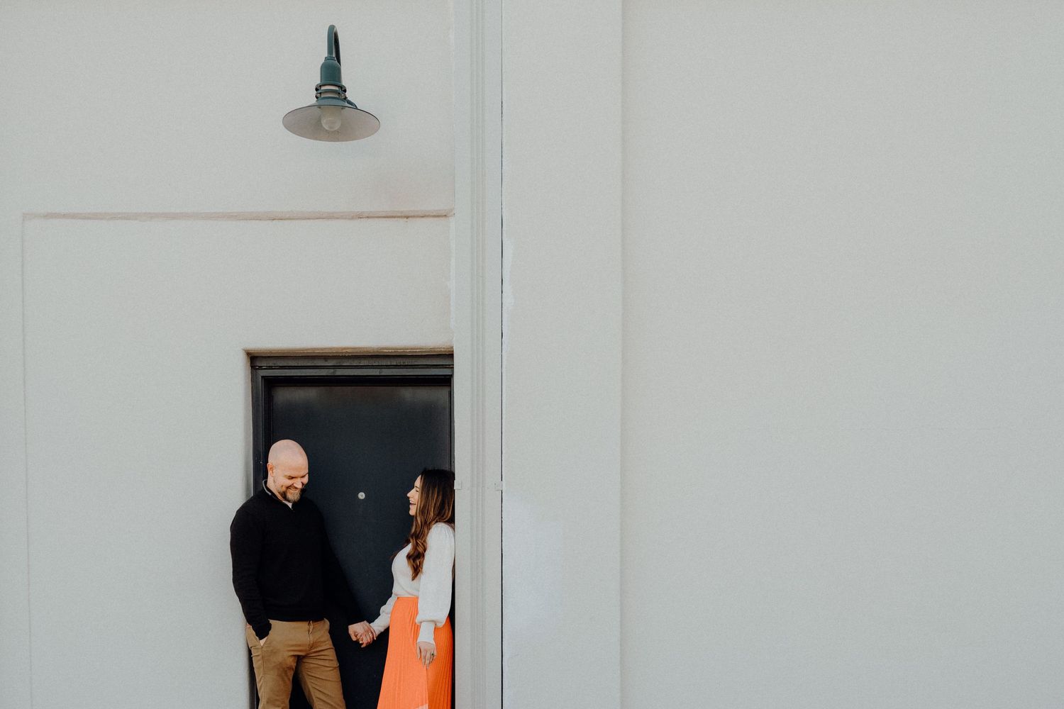 Minimalist composition of couple standing in white doorway.