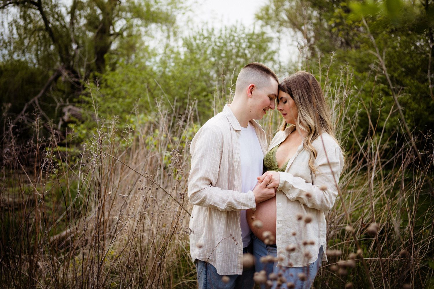 Intimate couple's portrait among tall grass and natural scenery.