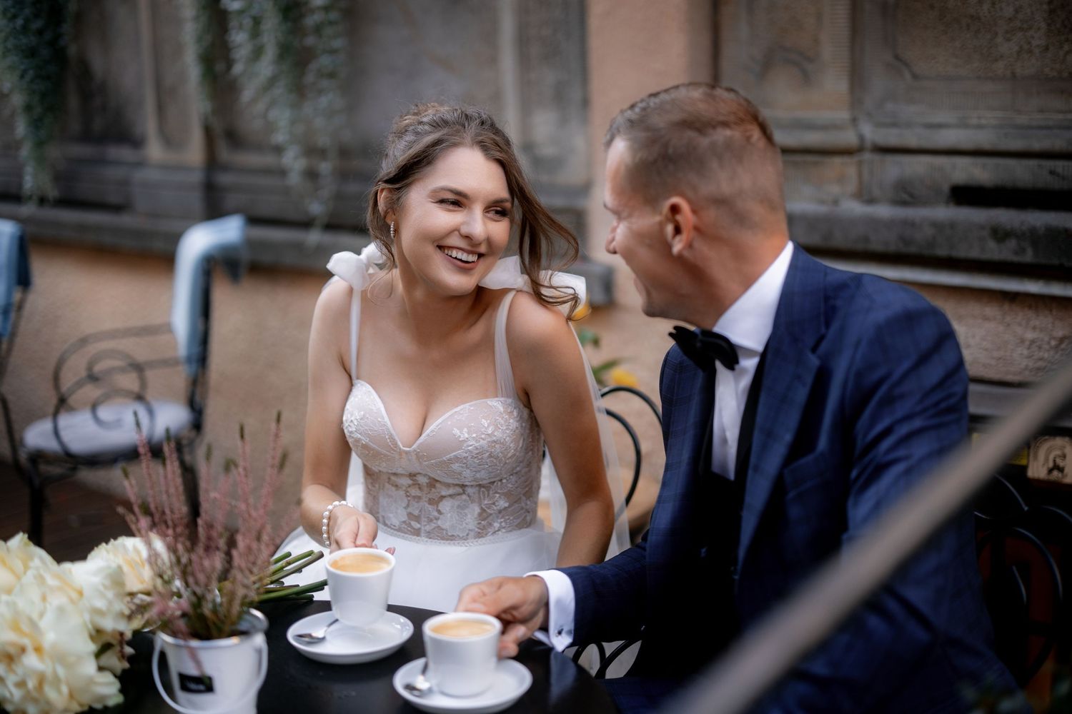 A couple sharing coffee and conversation at an outdoor cafe table.