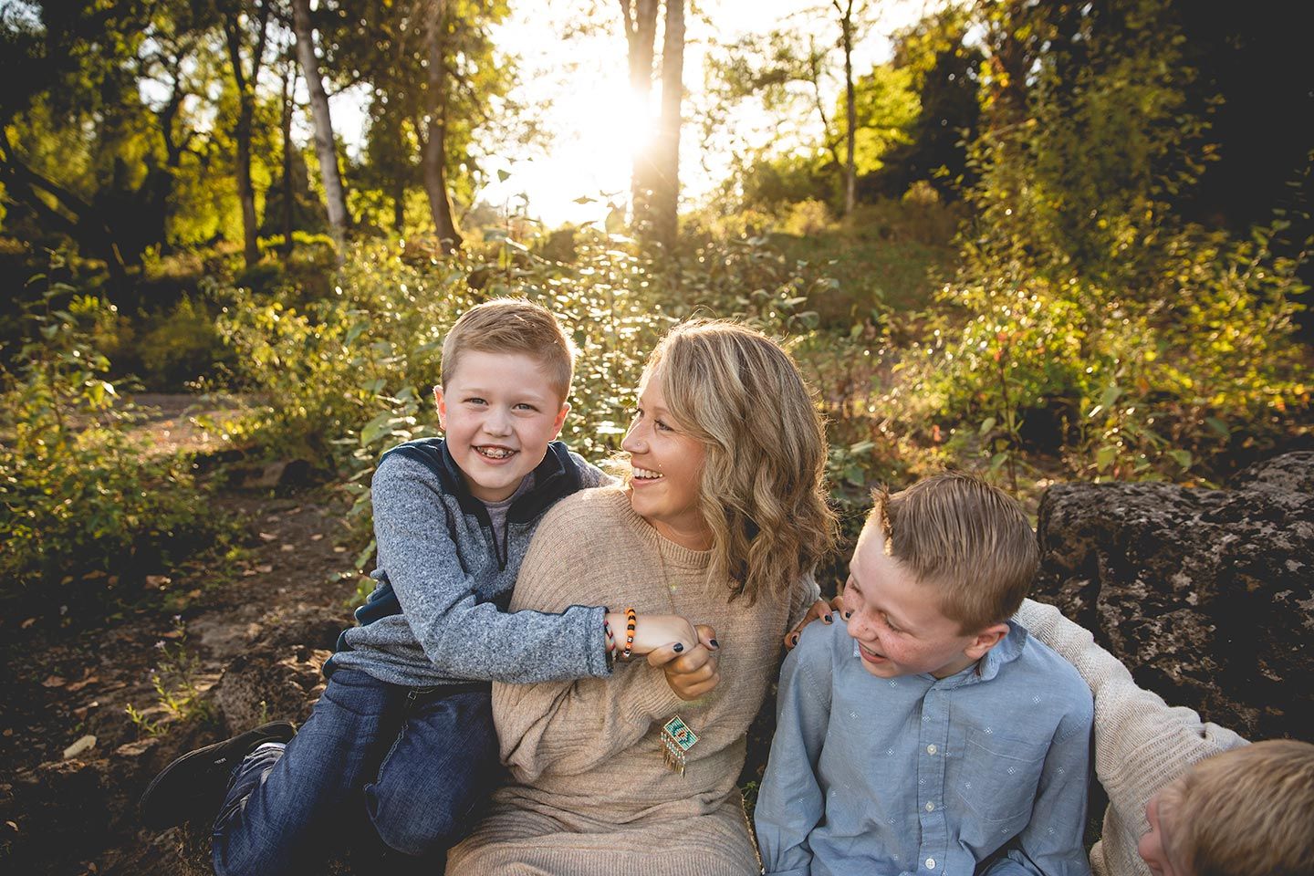mom with her three sons laughing and sitting on rocks