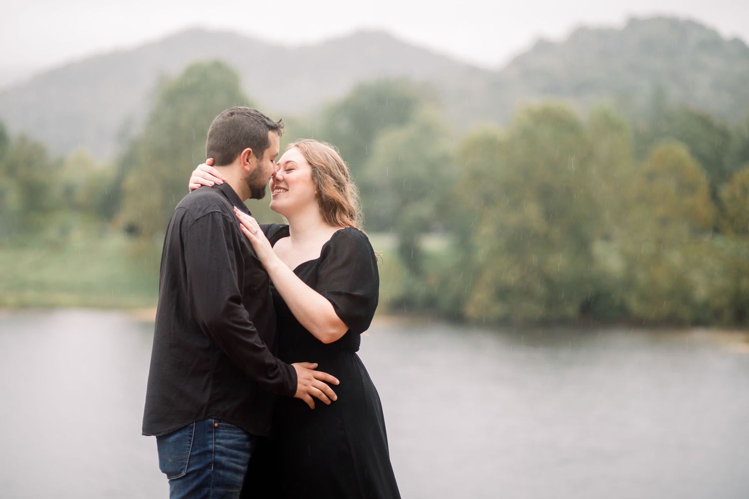 Romantic lakeside engagement session with misty mountains in the background.
