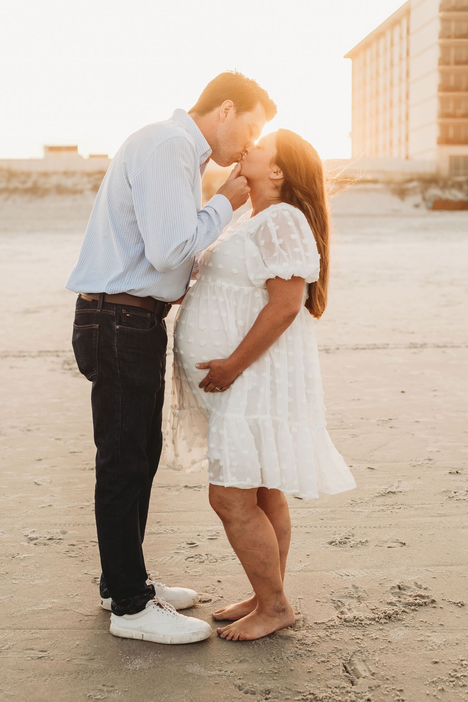 Couple sharing intimate moments on the beach at sunset.