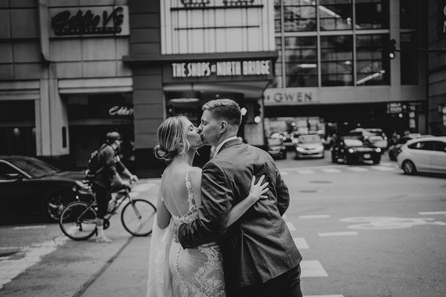 Urban wedding photo with cyclist passing in downtown city street.