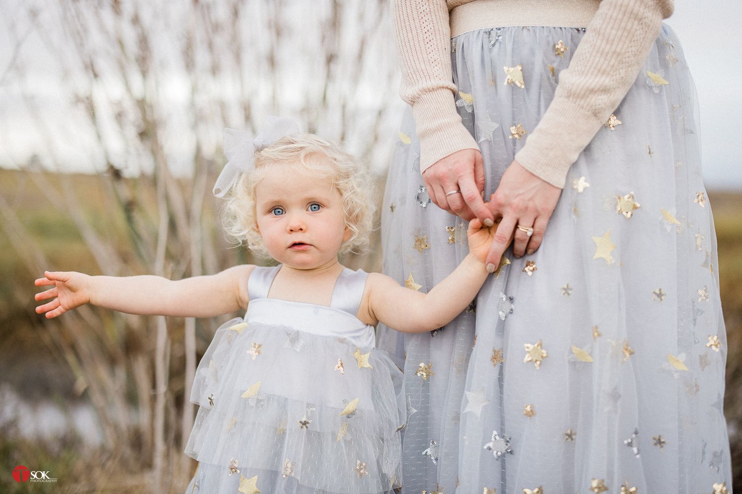 A light blue floral dress and cream sweater shown with small hands reaching outward.