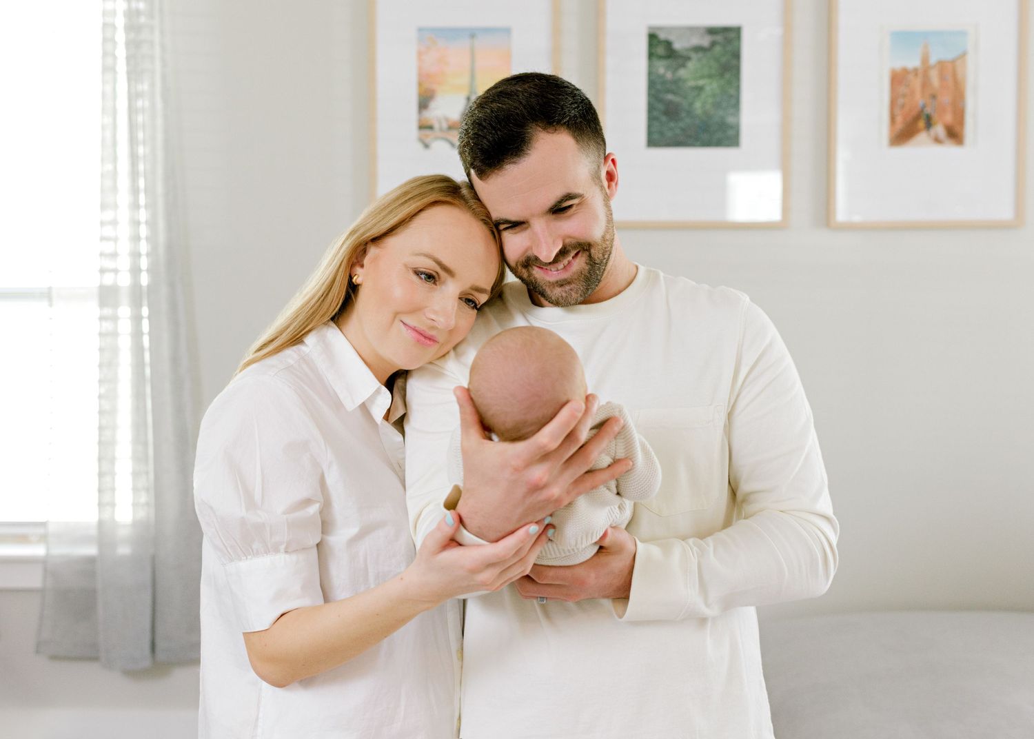 new parents holding up their newborn son, while staring at him with eyes full of love.