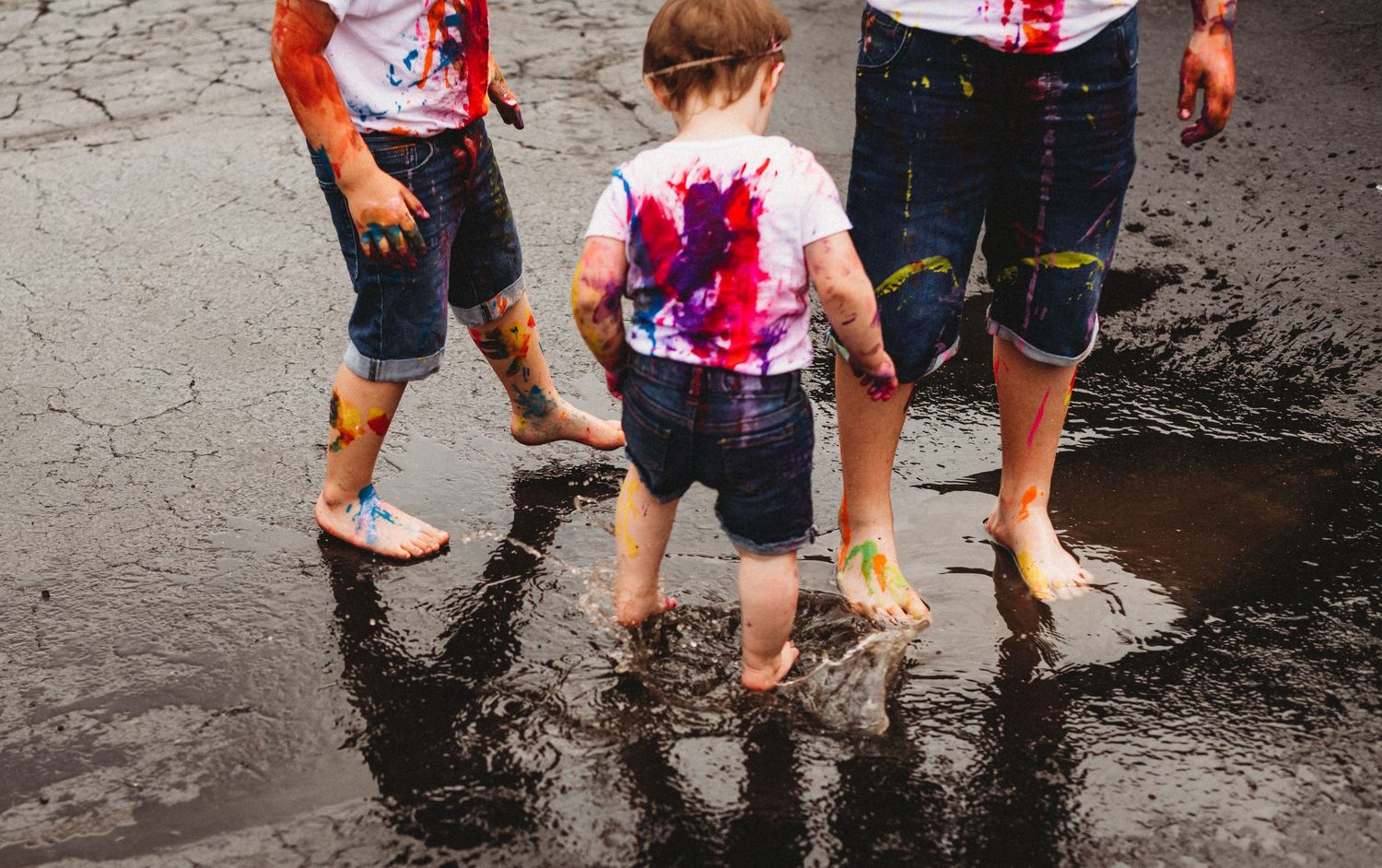 Children's feet splashing in puddles on rainy pavement.