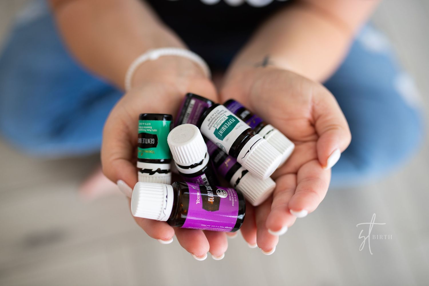 Samantha Tollison hands holding Young Living Essential Oil Bottles recommended for child birth