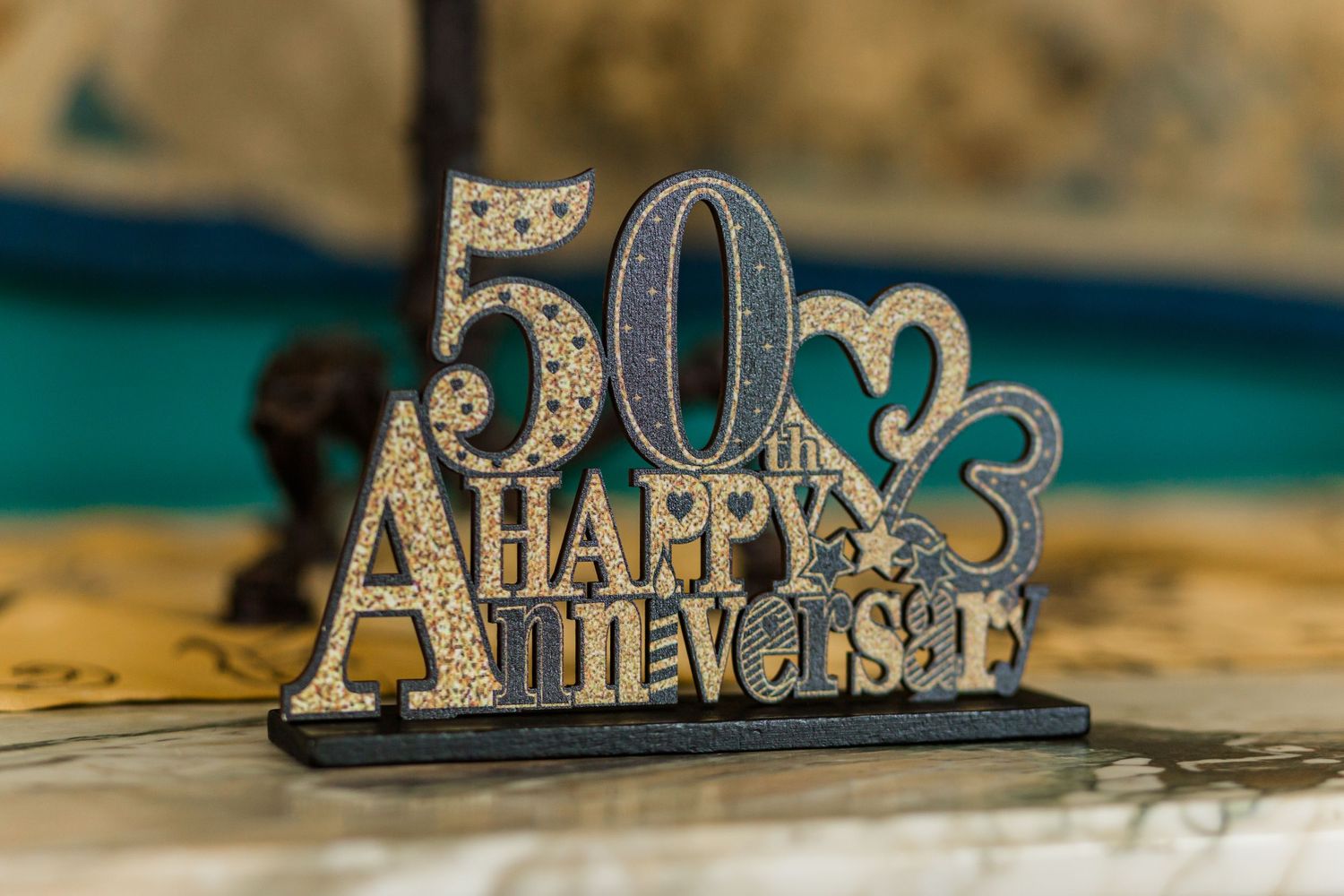 A decorative silver 50th anniversary table sign with glittery numbers and text.