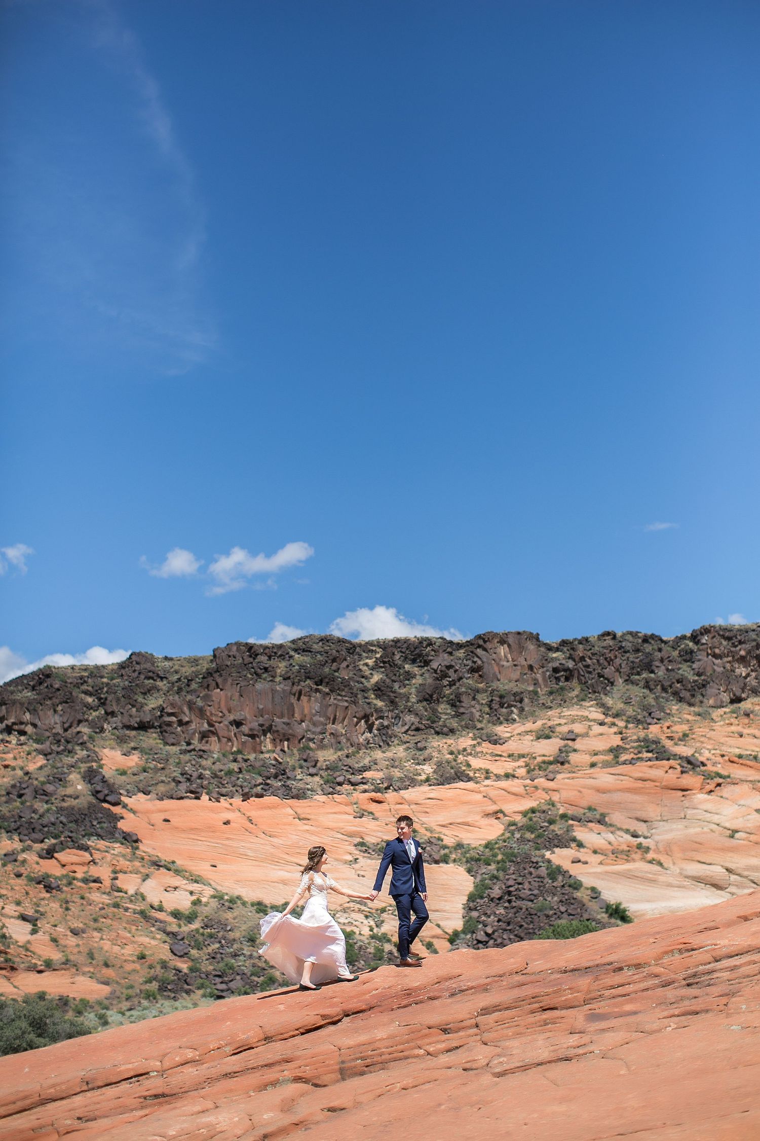 Bride and groom walking on the petrified dunes in Snow Canyon State Park, Utah during adventure destination wedding
