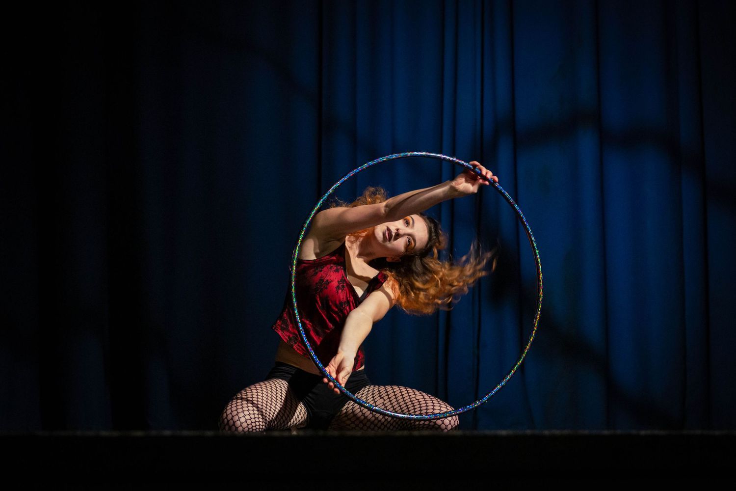 event photography of a circus performer on stage in a red leotard with a hoop