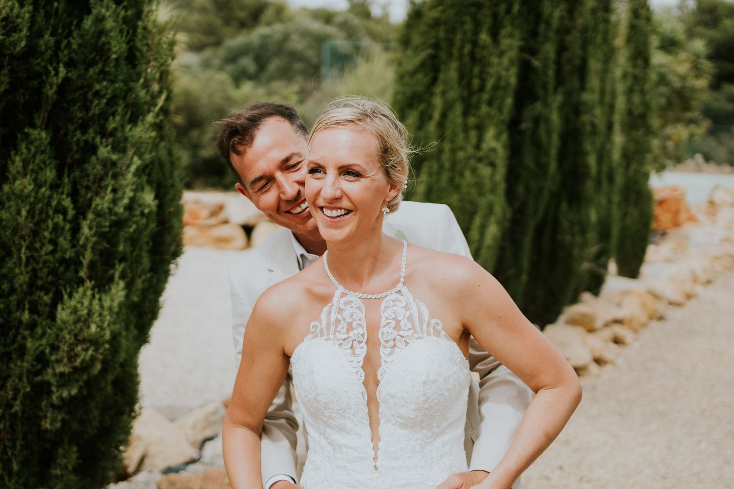 A happy couple sharing laughter among cypress trees at their wedding.