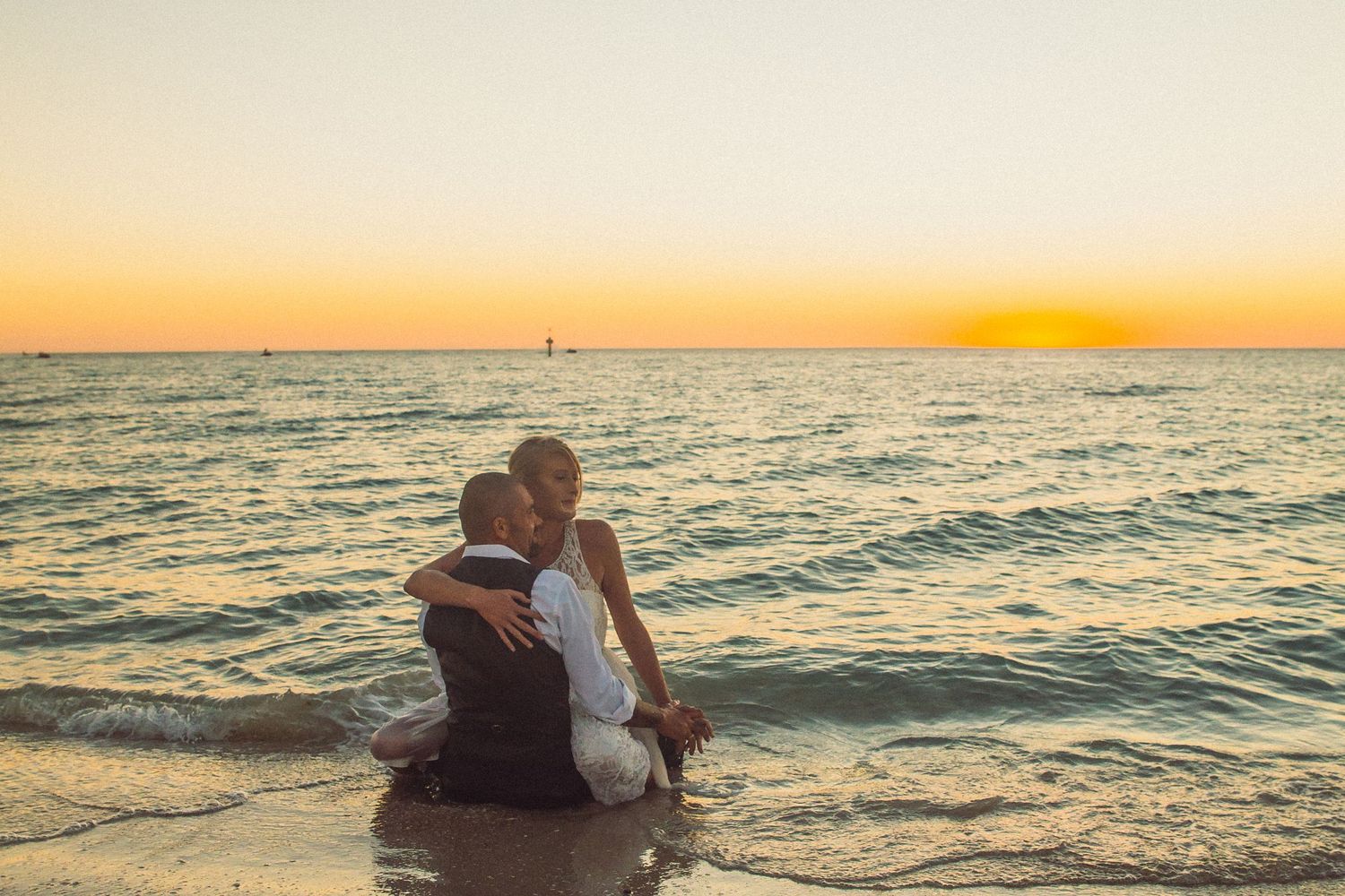 Elegant white dress flowing in ocean breeze on sandy beach at sunset.
