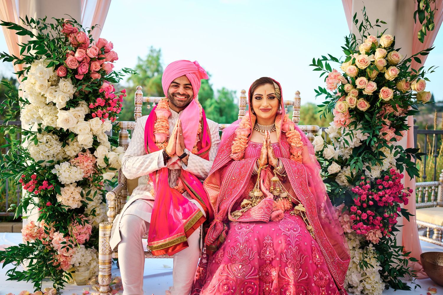 Traditional Indian wedding ceremony under floral arch with pink and peach roses.