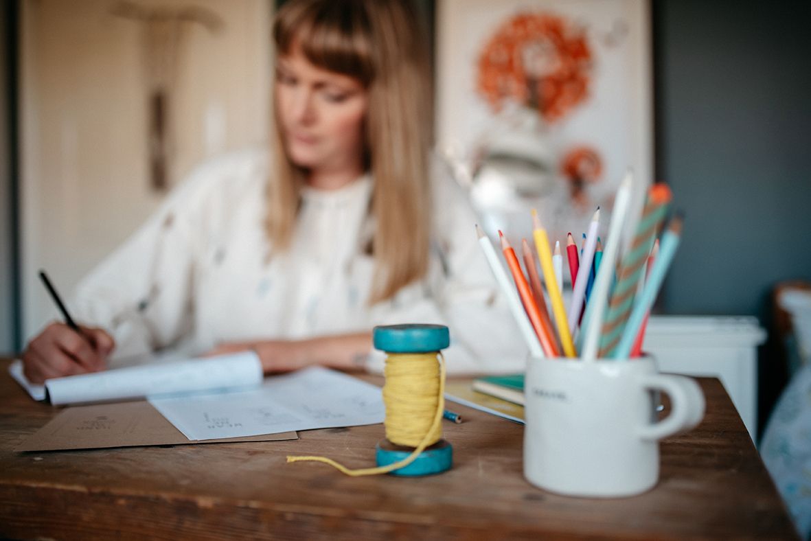 Creative workspace with art supplies and yellow mug on wooden desk.