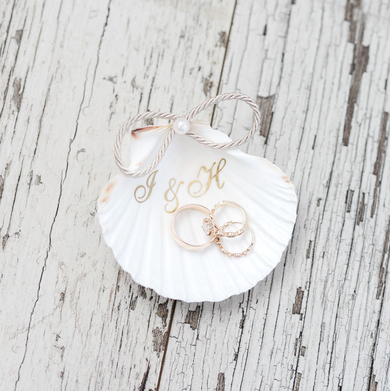 White seashells with rose gold accents arranged on distressed wood background.