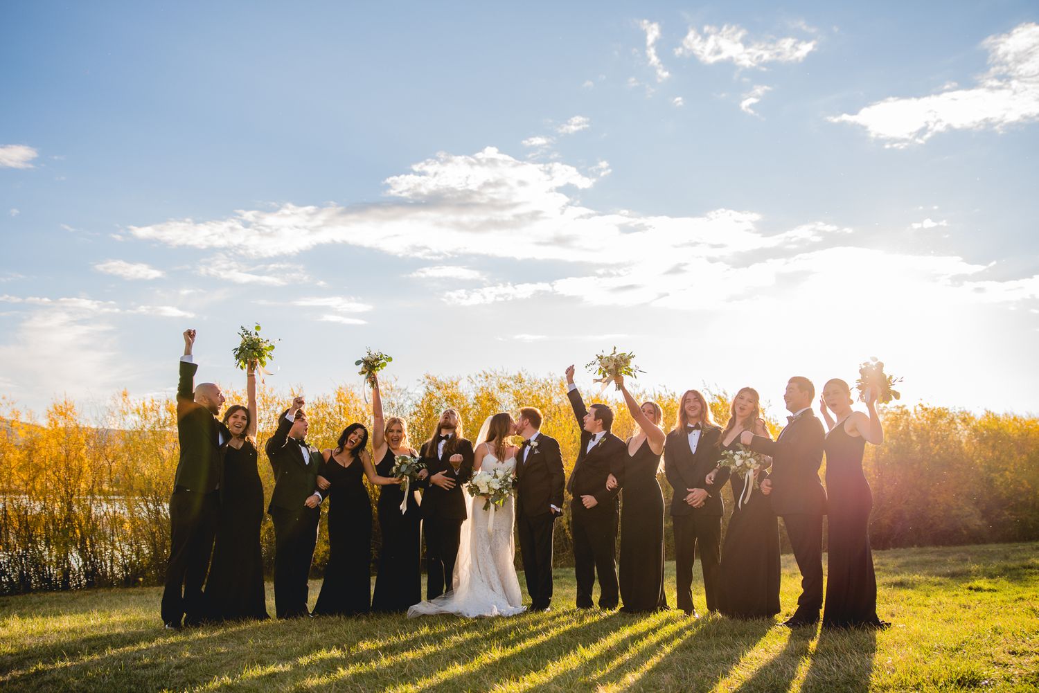 Wedding party celebrating outdoors at sunset with mountains in the background.