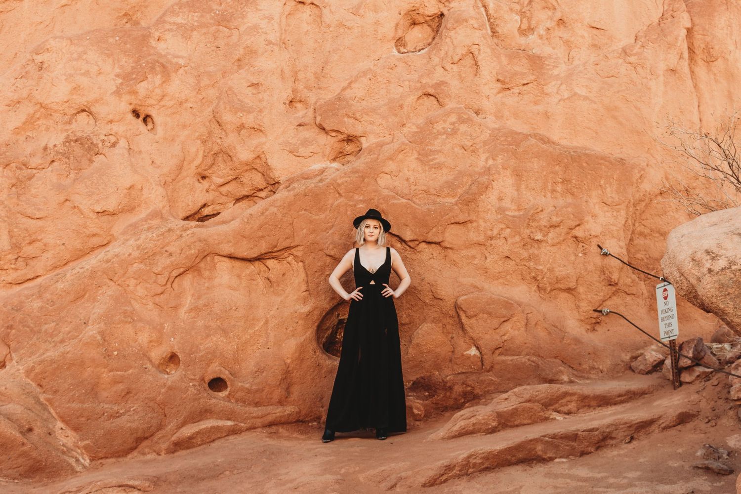 Black-clad figure posing against dramatic red rock formations in a desert landscape.