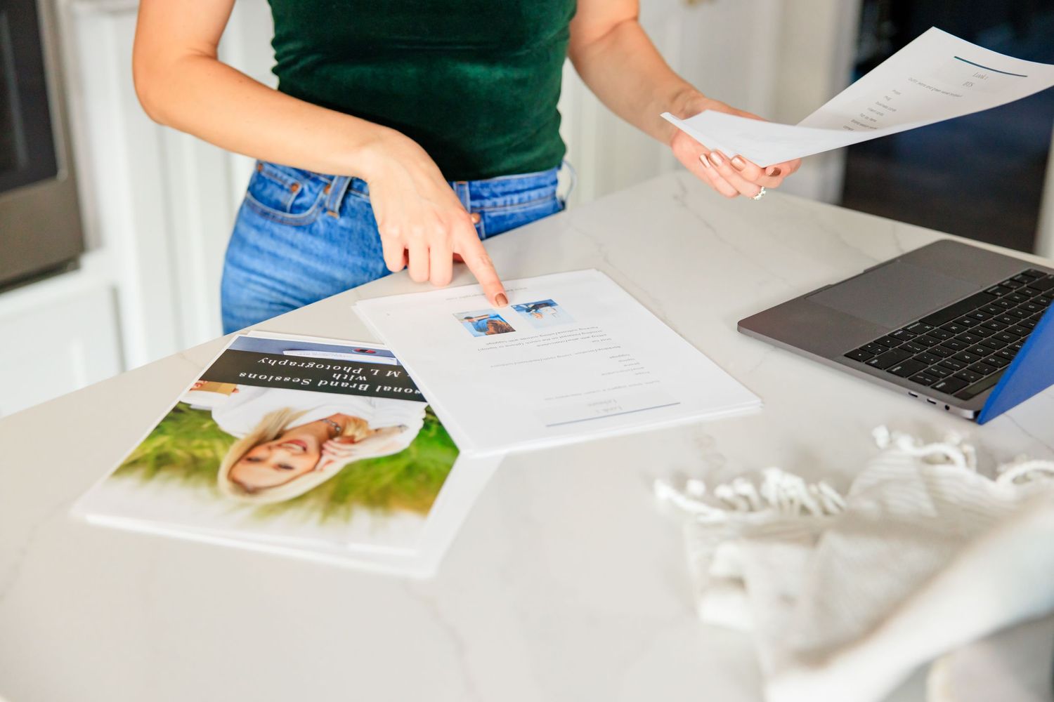 woman pointing at photographer business instructions with laptop and magazine