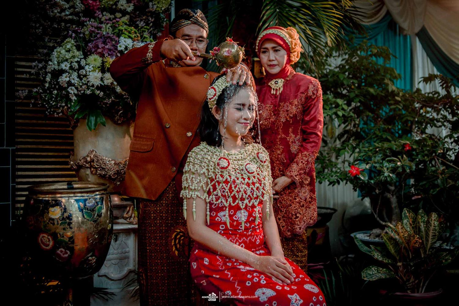 Traditional Indonesian wedding ceremony with cultural dress and customs being performed outdoors.