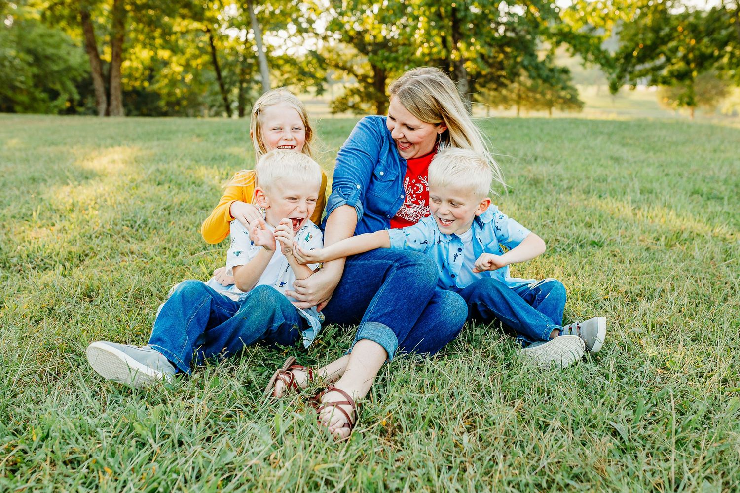 Candid family moment captured during sunset photoshoot in grassy field.