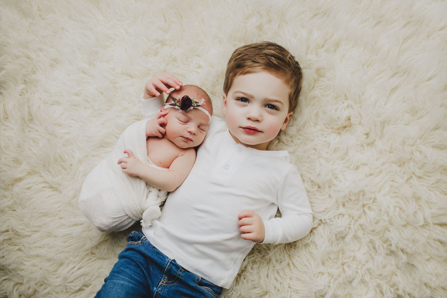 Young siblings lying on cream colored carpet during portrait session.