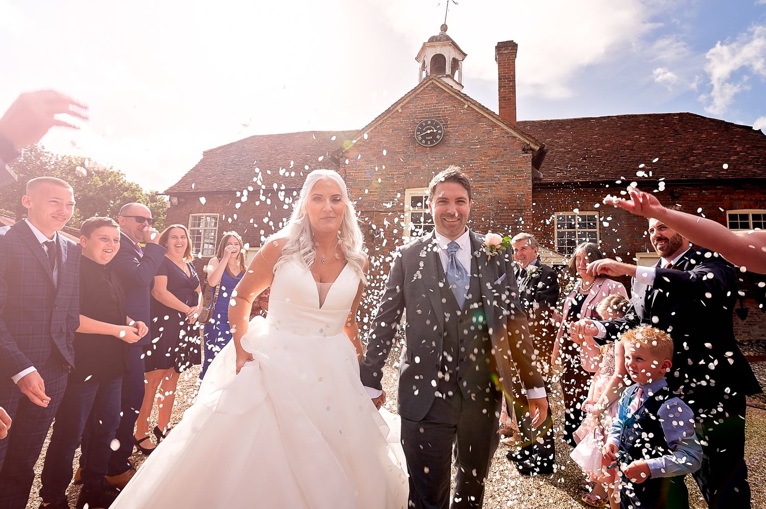 Joyful wedding celebration with confetti being thrown outside brick church.