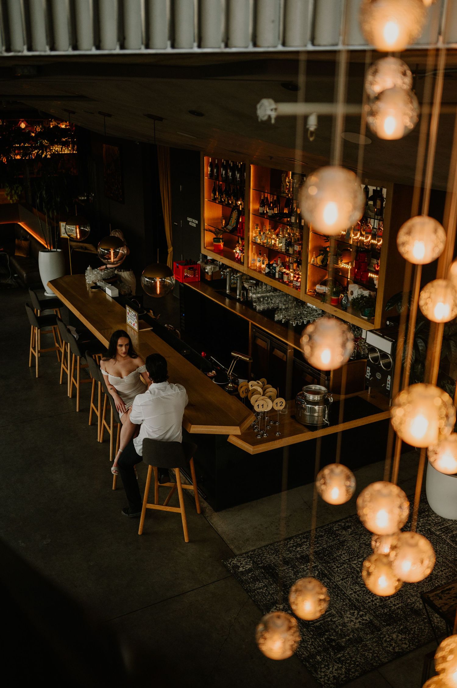 Modern bar interior with hanging pendant lights and empty barstools.