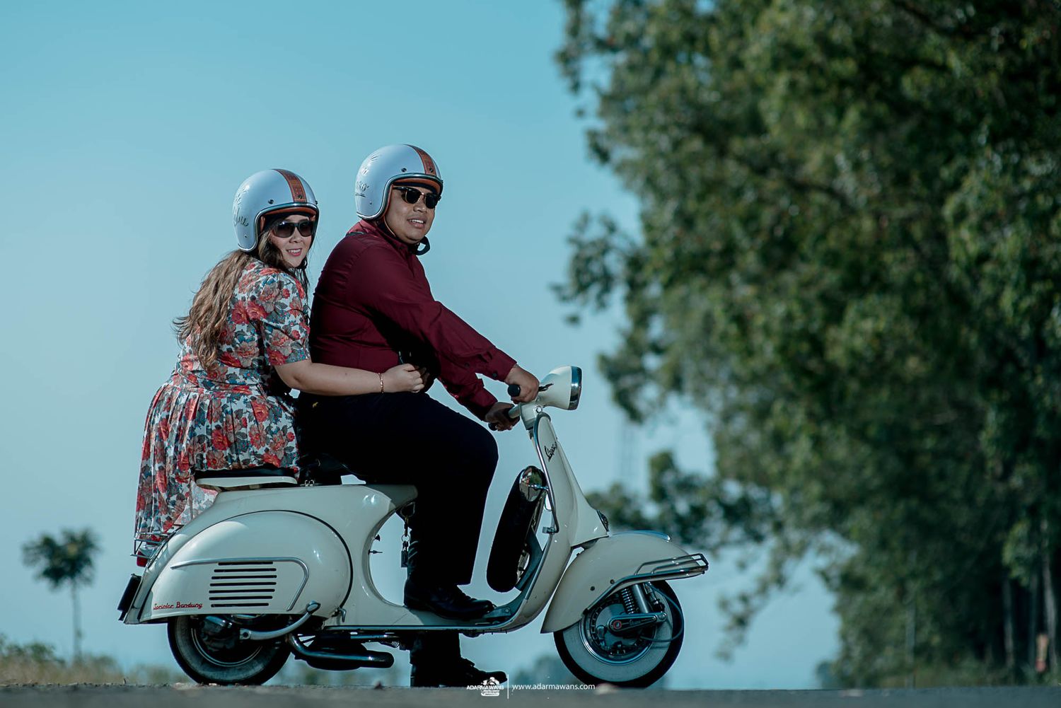 Couple riding vintage Vespa scooter in retro-styled photoshoot.