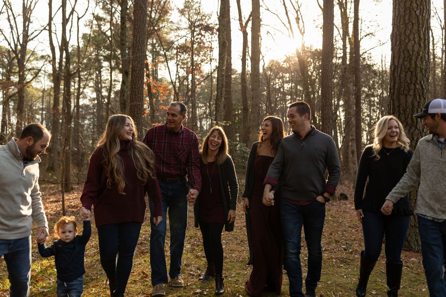 A group of people walking together through a sunlit autumn forest.