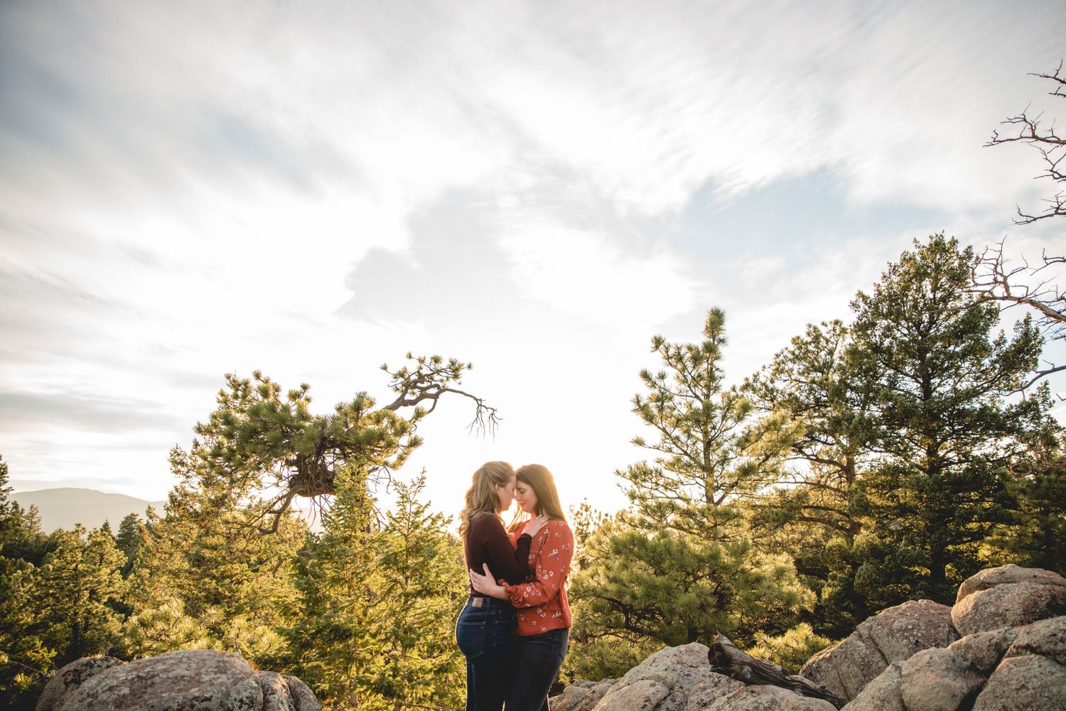 Romantic sunset portrait among pine trees and rocks in mountain setting.