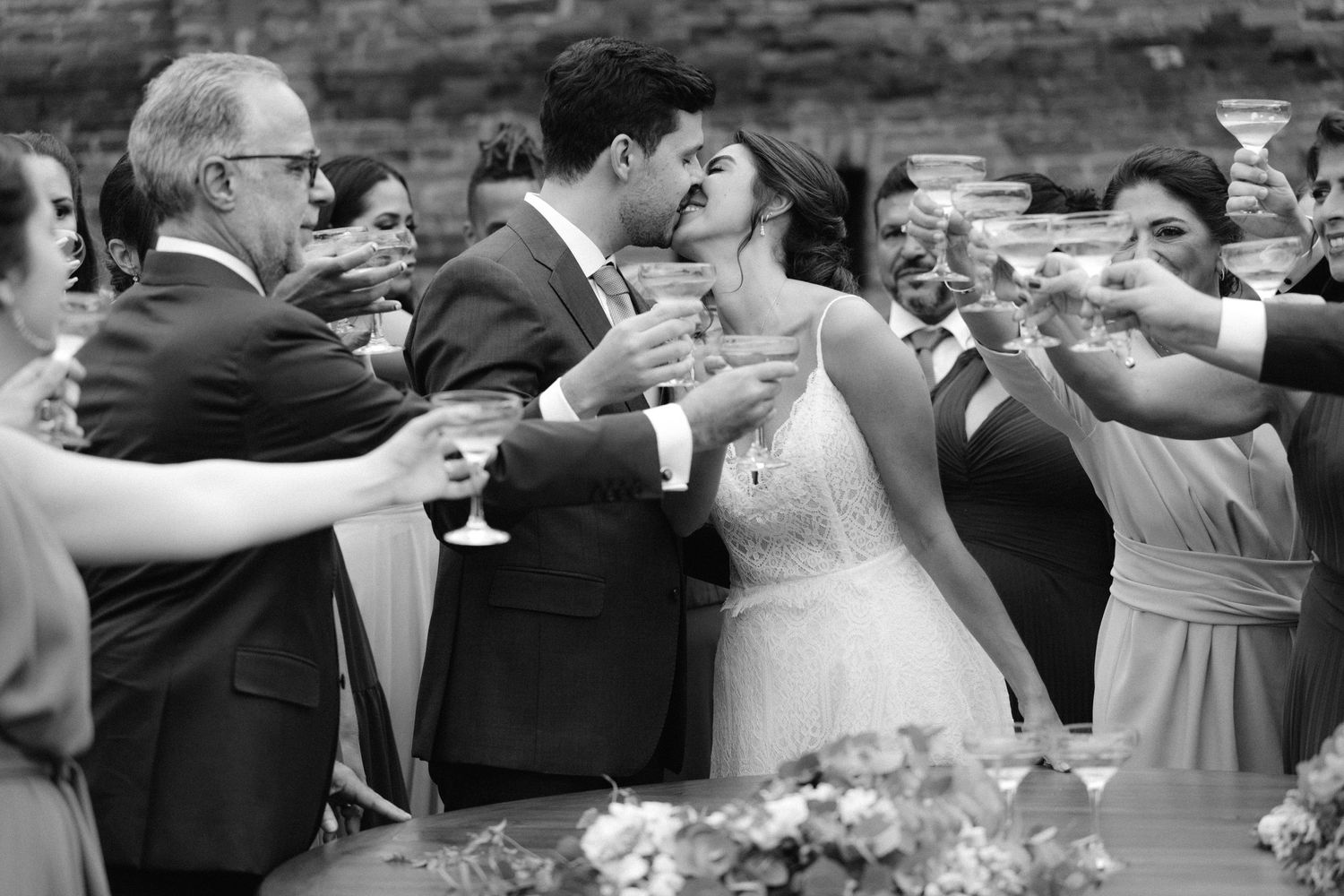 Wedding party toasts with champagne during outdoor celebration in black and white.