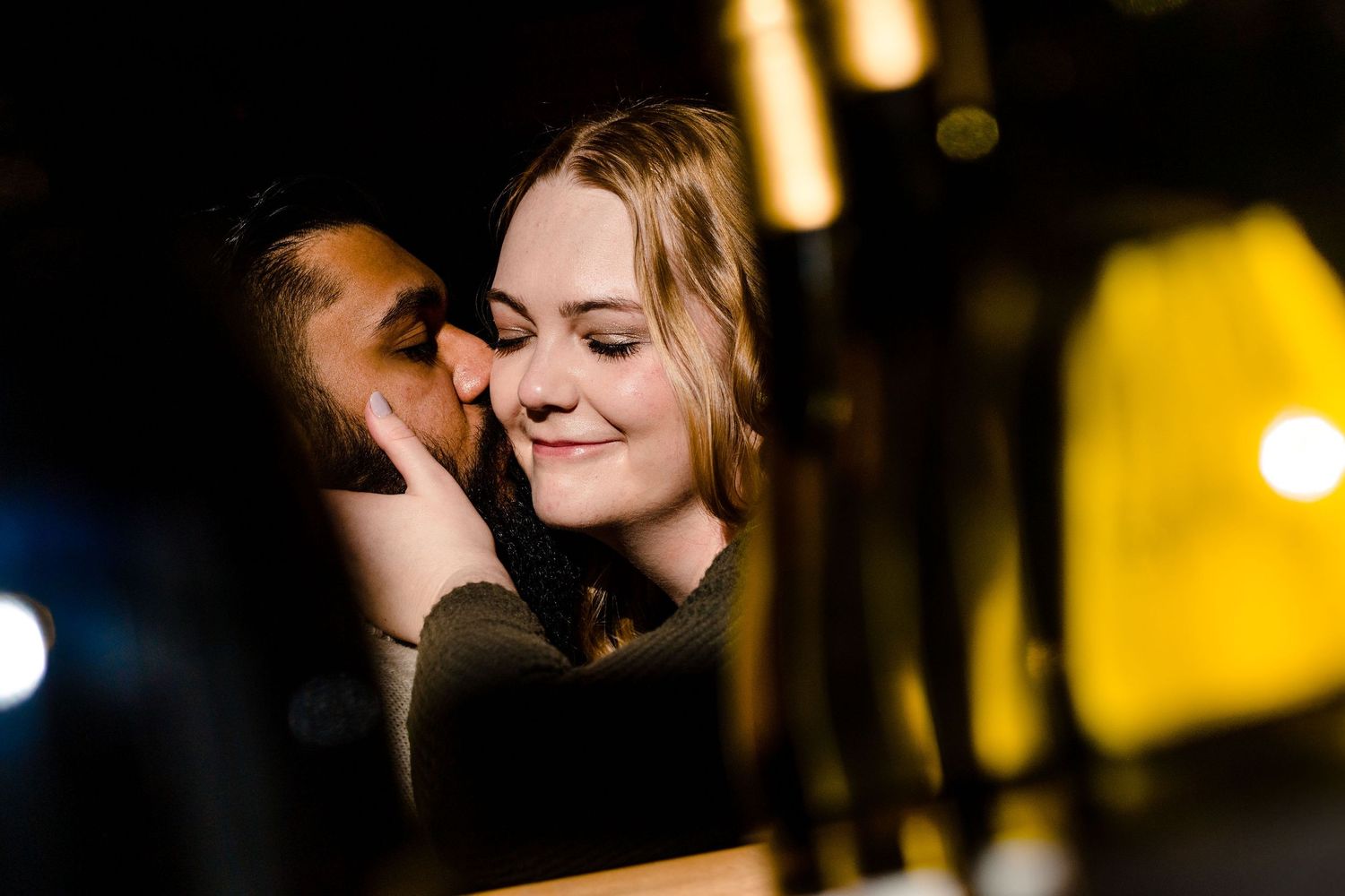 Intimate close-up of couple sharing romantic moment in dim evening lighting.