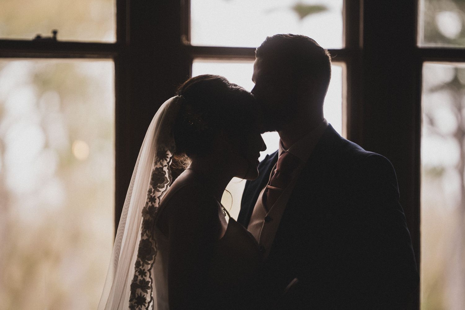 A romantic silhouette of a couple sharing an intimate moment by a window.
