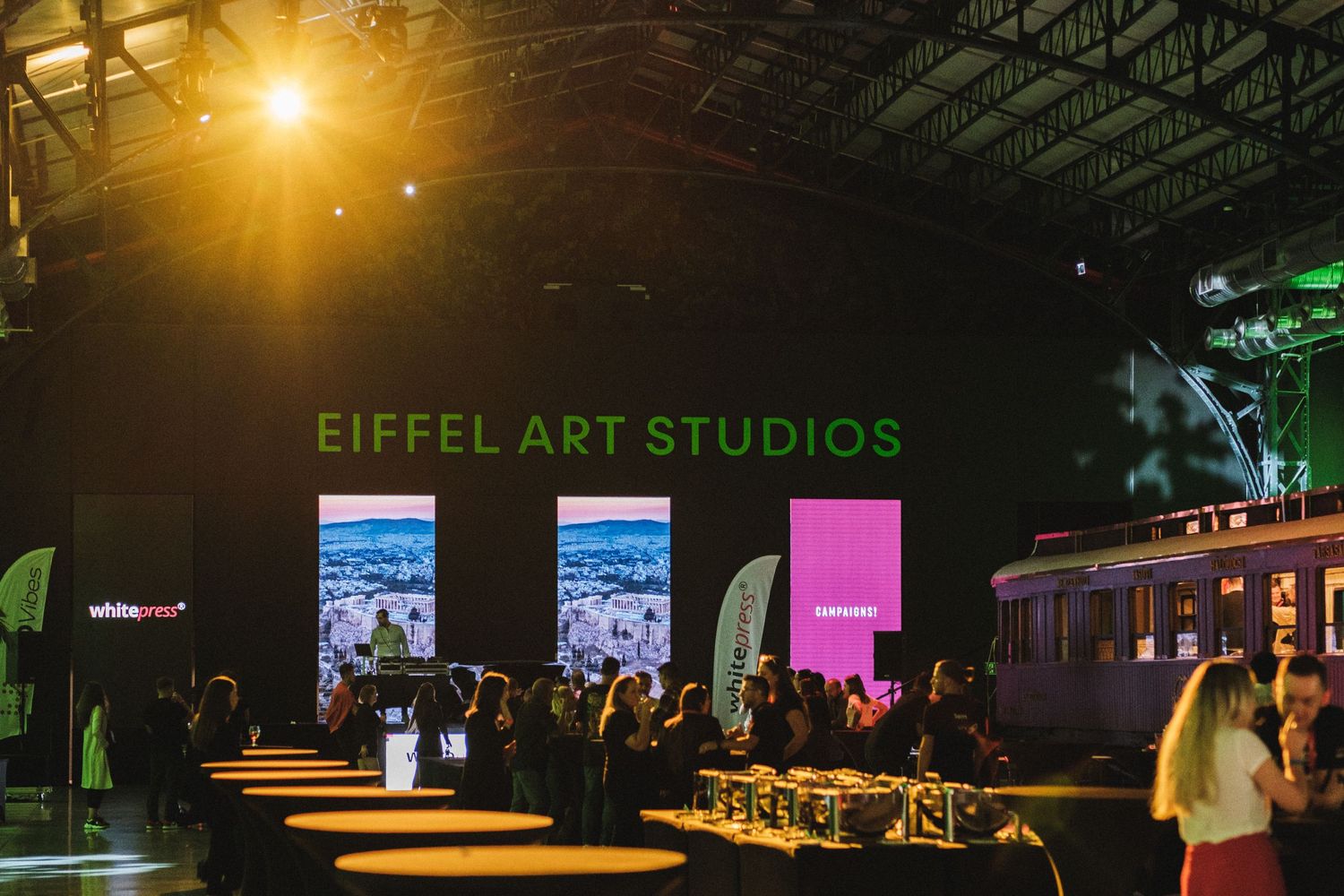 Event space at Eiffel Art Studios illuminated with warm lighting and people gathering.