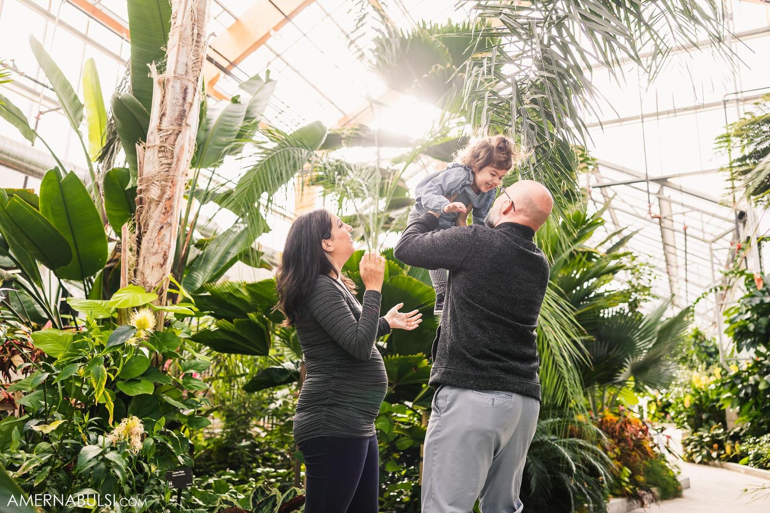Family moment captured in a greenhouse surrounded by tropical plants.