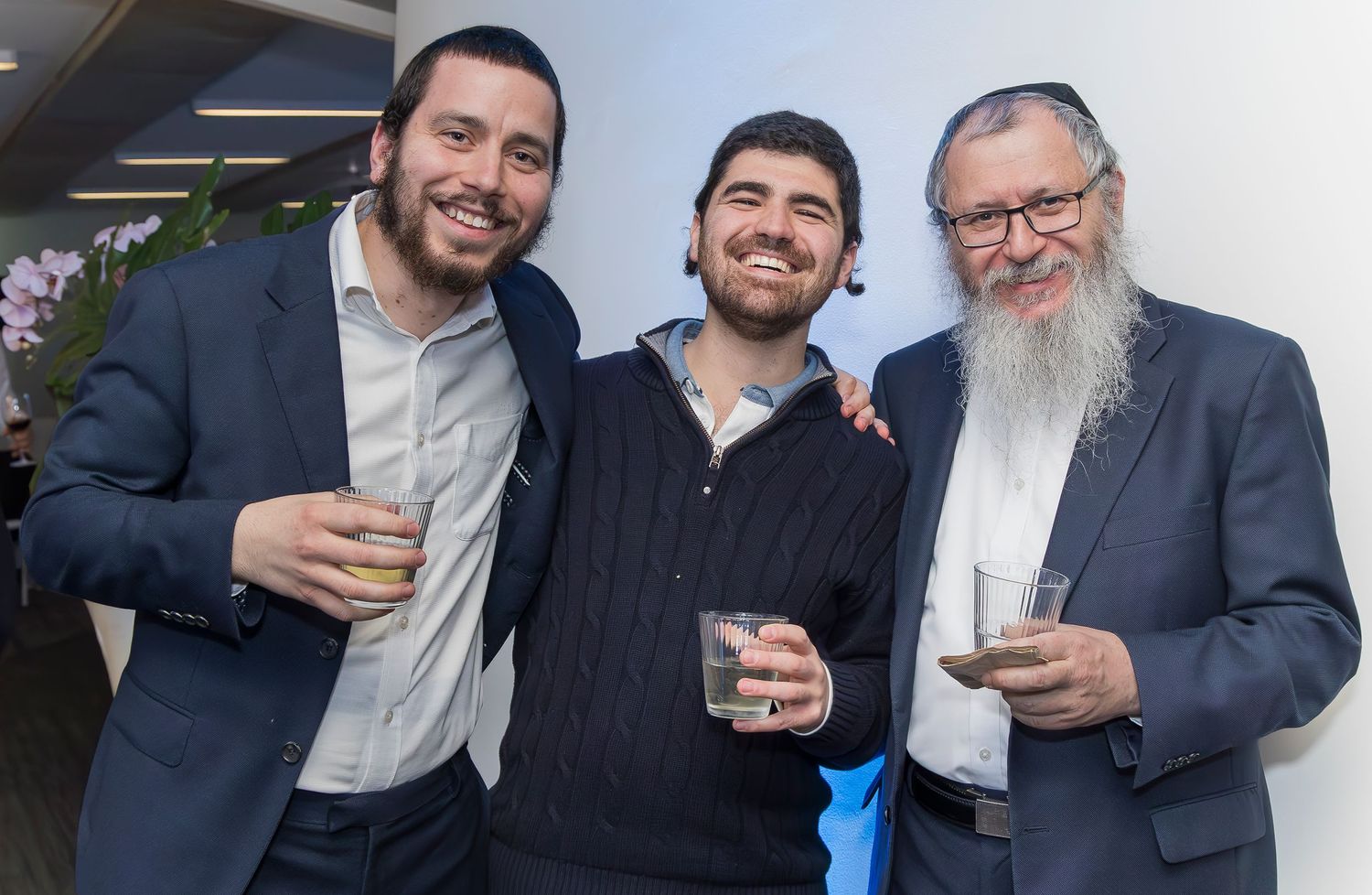 Three men in business attire sharing drinks at a social gathering.
