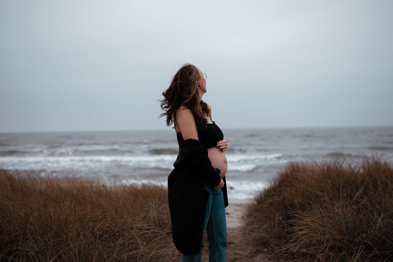 A silhouette against a moody oceanscape with waves and cloudy skies.